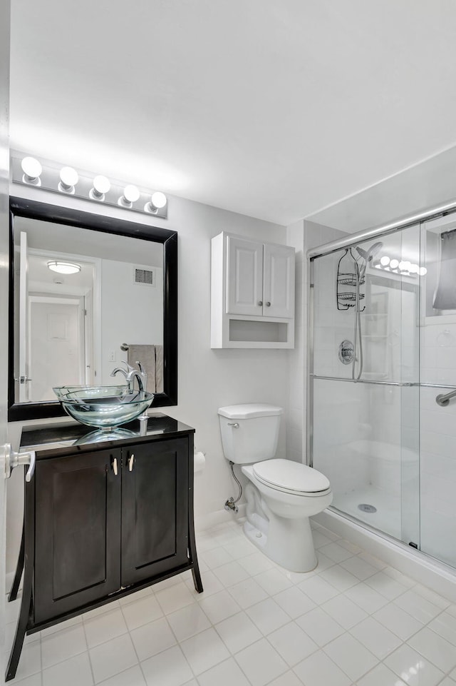 bathroom featuring tile patterned flooring, vanity, toilet, and a shower with shower door