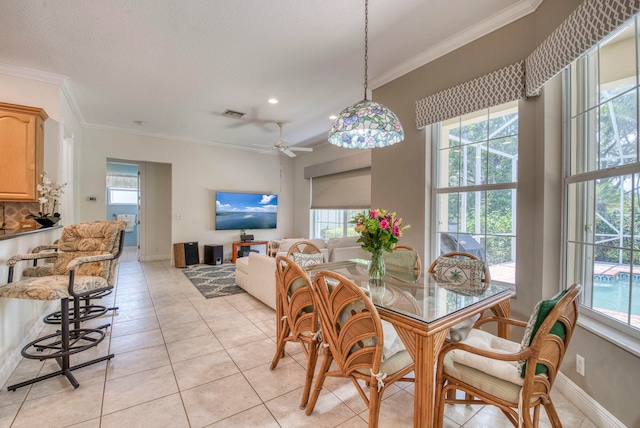 tiled dining room with ornamental molding, ceiling fan, and a healthy amount of sunlight