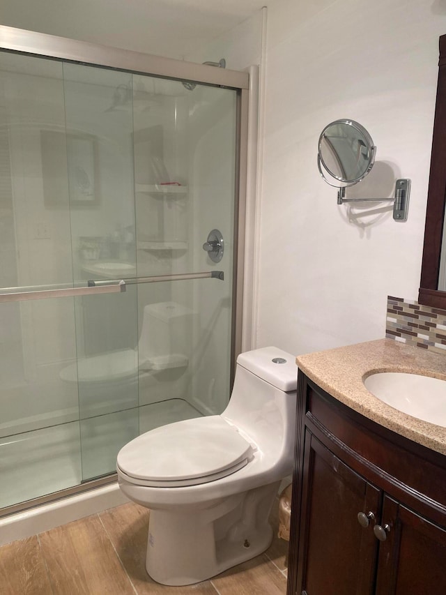 bathroom featuring hardwood / wood-style floors, a shower with door, vanity, and toilet