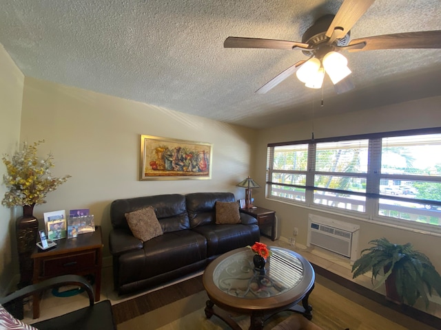 living room featuring hardwood / wood-style flooring, a wall unit AC, a textured ceiling, and ceiling fan