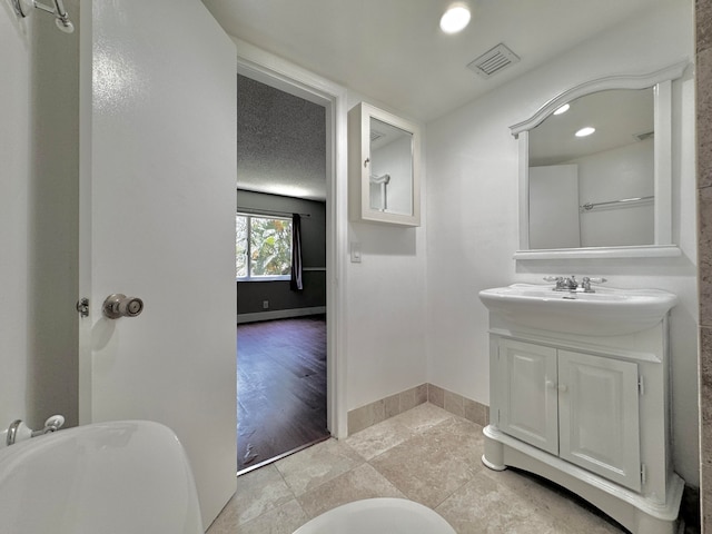 bathroom with vanity, a textured ceiling, and hardwood / wood-style floors