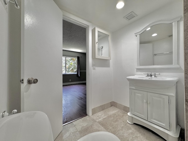 bathroom with baseboards, visible vents, a textured ceiling, vanity, and recessed lighting