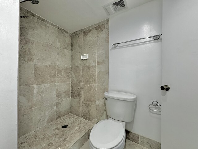 bathroom with tiled shower and toilet