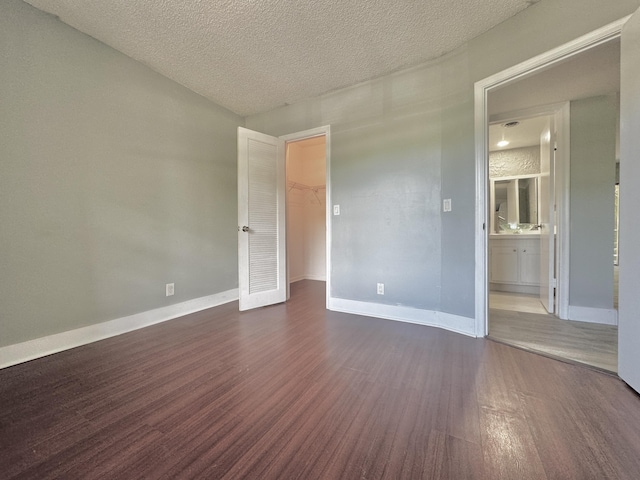 unfurnished room featuring dark wood-style floors, a textured ceiling, and baseboards