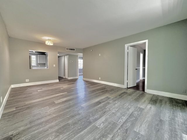 unfurnished room featuring baseboards, visible vents, and wood finished floors