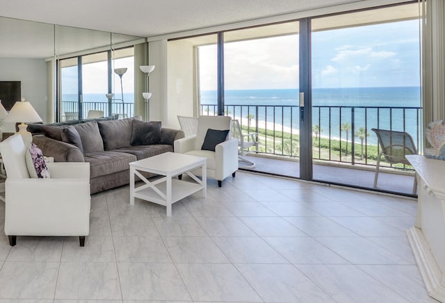 tiled living room with plenty of natural light, a water view, and floor to ceiling windows