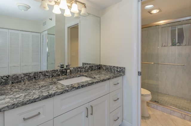 bathroom featuring tile patterned floors, a shower with shower door, toilet, and vanity