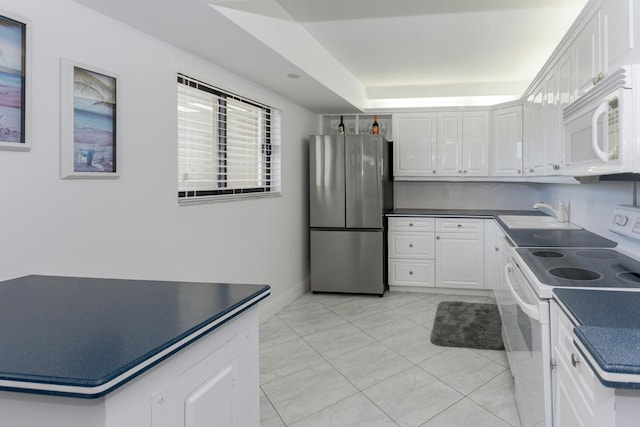 kitchen with white appliances, sink, light tile patterned flooring, white cabinetry, and a raised ceiling