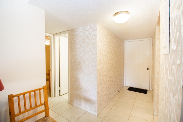 hallway featuring a textured ceiling and light tile patterned flooring