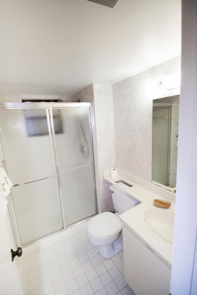 bathroom featuring toilet, an enclosed shower, vanity, and tile patterned floors