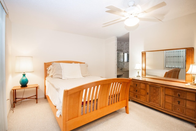 bedroom with light carpet, ensuite bath, and ceiling fan