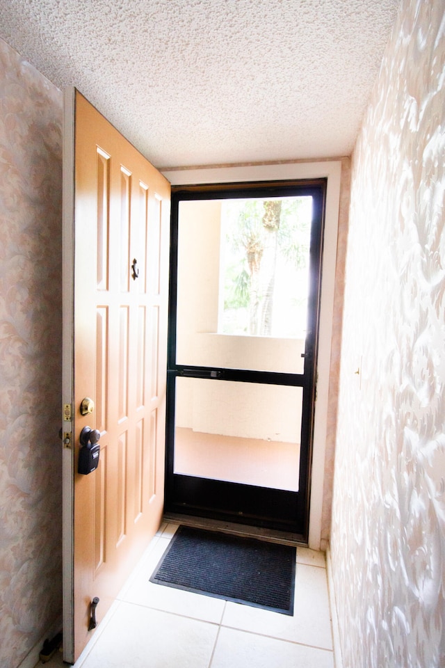 doorway with a textured ceiling and light tile patterned floors