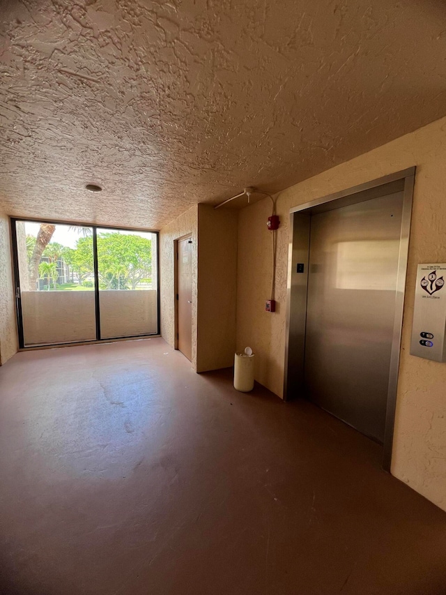 unfurnished room featuring a textured ceiling and elevator