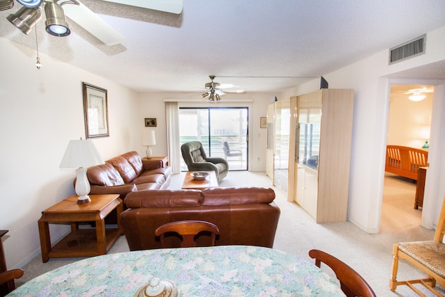 carpeted living room with a textured ceiling and ceiling fan