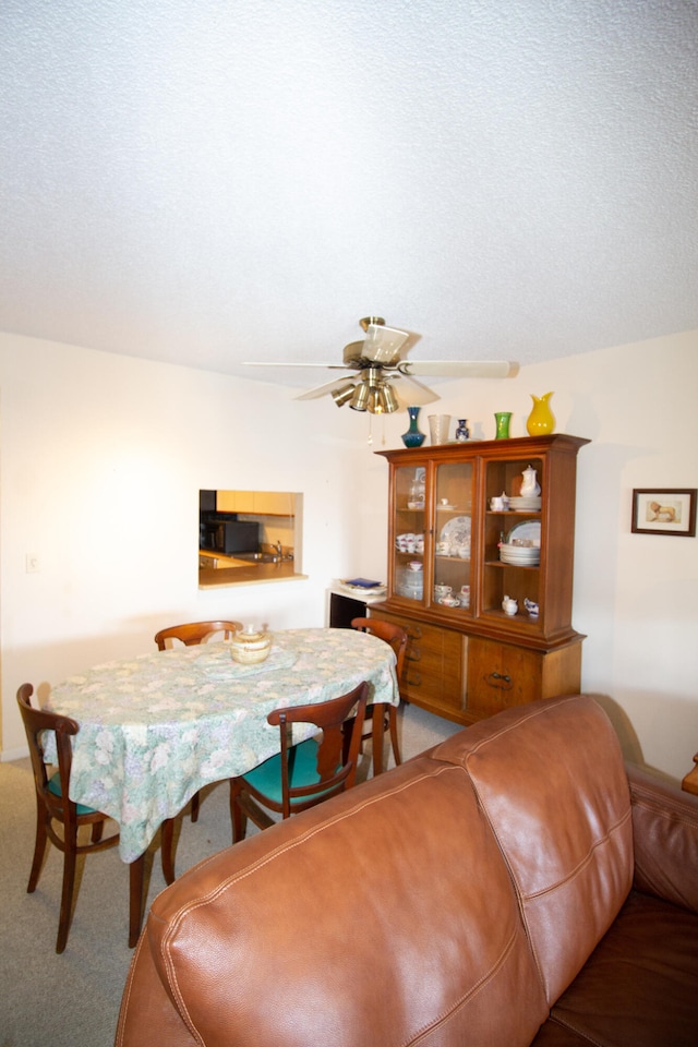 dining space with a textured ceiling, carpet floors, and ceiling fan