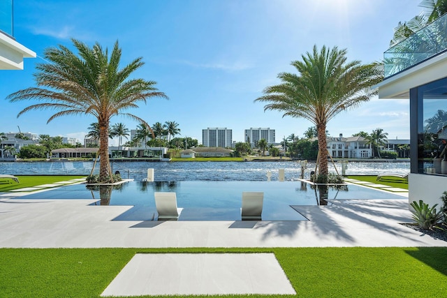 view of swimming pool with a water view and a lawn