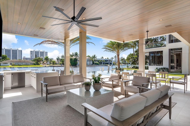 view of patio / terrace featuring a water view, ceiling fan, an outdoor living space, and an outdoor kitchen