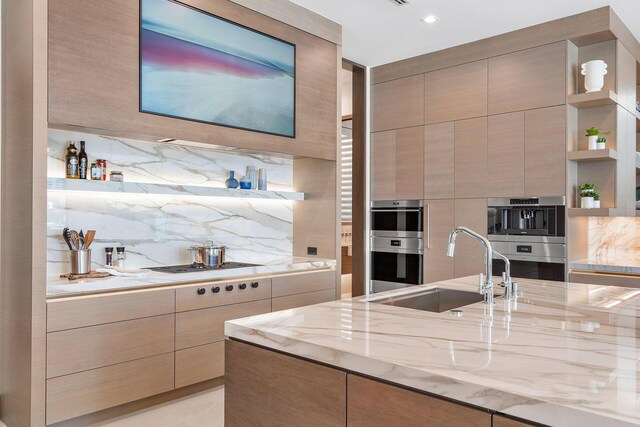 kitchen featuring stainless steel double oven, light stone countertops, sink, and backsplash