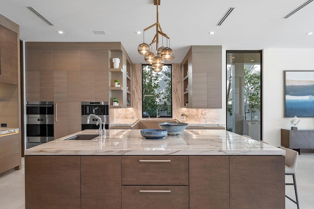 kitchen with an inviting chandelier, sink, light stone countertops, double oven, and decorative light fixtures