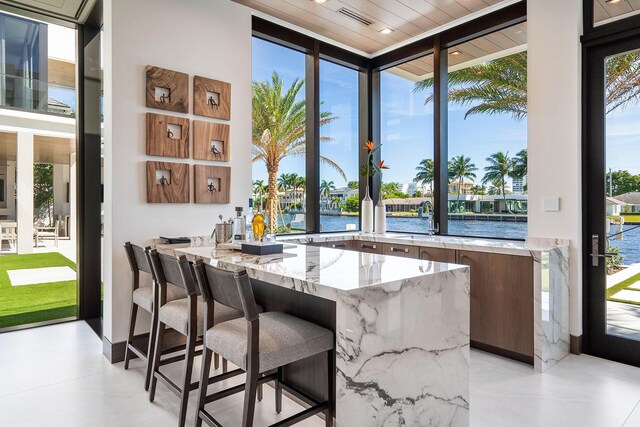 bar with a water view, sink, and light stone counters