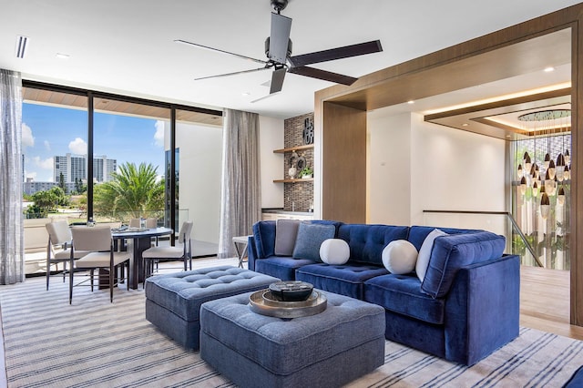 living room featuring ceiling fan and a wall of windows