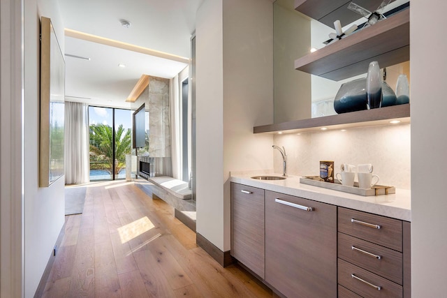 interior space with tasteful backsplash, sink, floor to ceiling windows, and light wood-type flooring