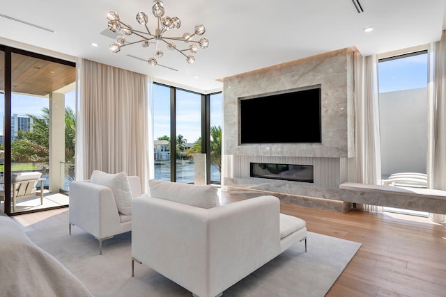 living room featuring a notable chandelier, floor to ceiling windows, a fireplace, and a wealth of natural light