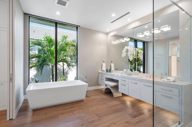 bathroom featuring vanity, a bathing tub, expansive windows, and wood-type flooring