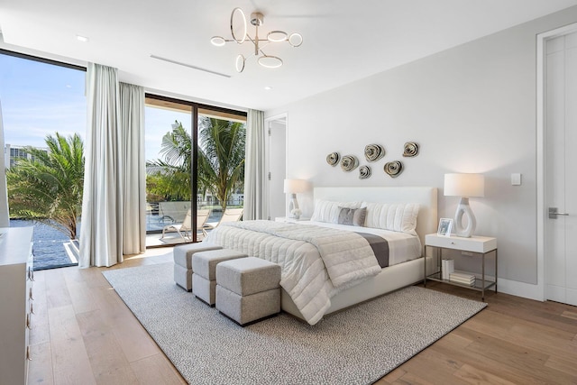 bedroom with a chandelier, access to exterior, a wall of windows, and light hardwood / wood-style flooring