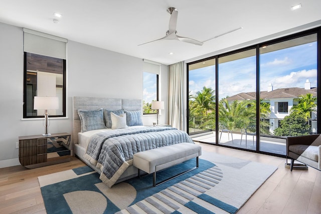 bedroom featuring ceiling fan, access to outside, a wall of windows, and light hardwood / wood-style flooring