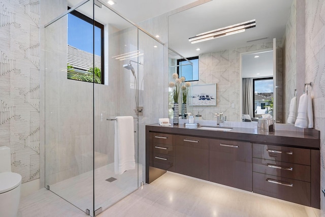 bathroom featuring a shower with door, vanity, tile walls, and toilet