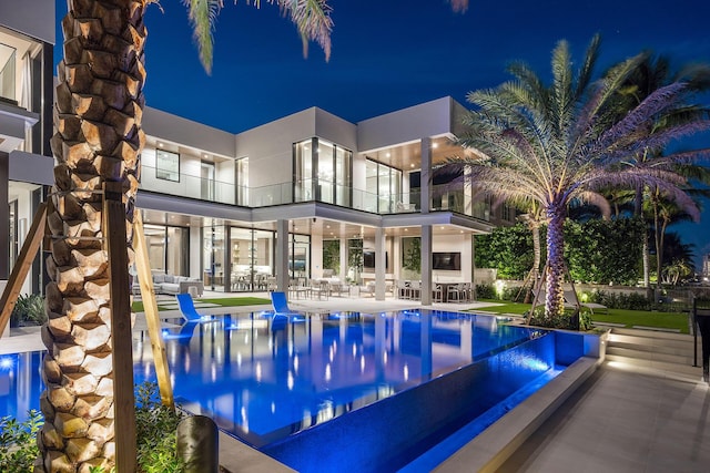 pool at night featuring a patio area