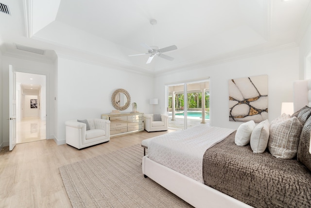 bedroom featuring crown molding, a tray ceiling, light wood-type flooring, and access to outside