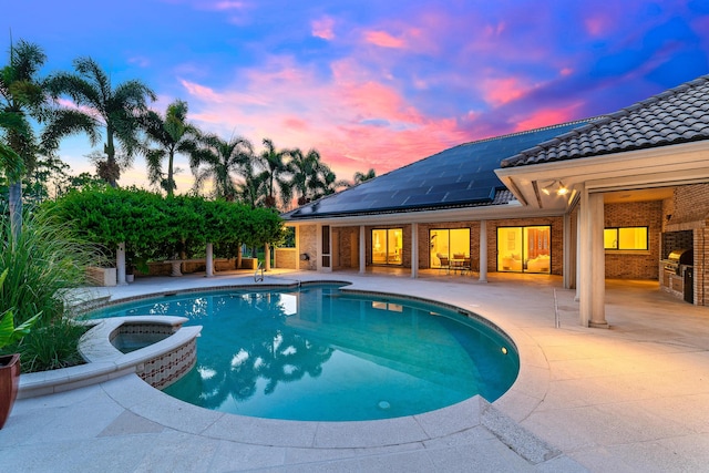 pool at dusk featuring an in ground hot tub, area for grilling, and a patio