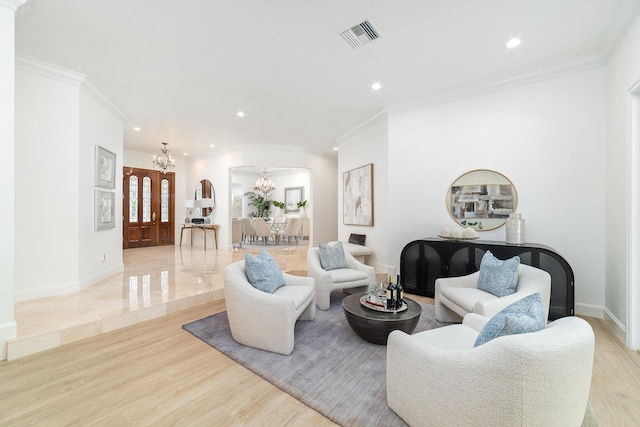 living room with an inviting chandelier, crown molding, and light hardwood / wood-style flooring