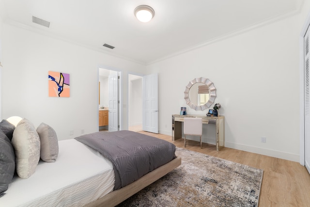 bedroom with connected bathroom, light wood-type flooring, and ornamental molding