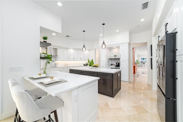 kitchen featuring refrigerator, white cabinetry, a center island, light stone counters, and kitchen peninsula