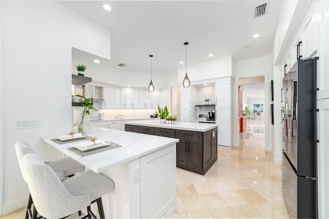 kitchen with a kitchen bar, white cabinets, high end black fridge, light tile patterned floors, and a kitchen island