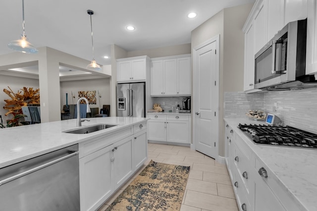 kitchen with decorative backsplash, white cabinetry, stainless steel appliances, decorative light fixtures, and sink