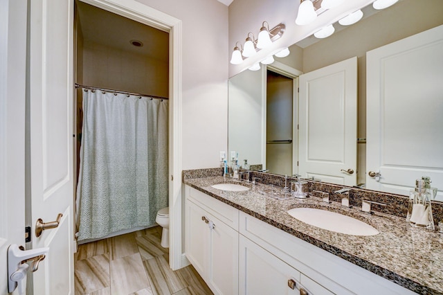 bathroom with walk in shower, vanity, and toilet