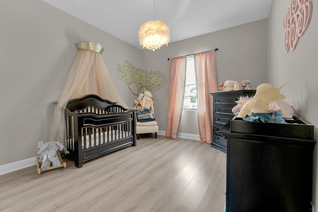 bedroom featuring an inviting chandelier, a nursery area, and hardwood / wood-style floors