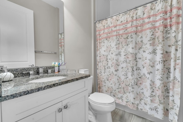 bathroom featuring tile patterned flooring, walk in shower, vanity, and toilet