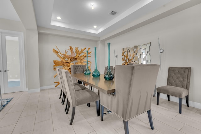 dining room with a tray ceiling and light tile patterned floors