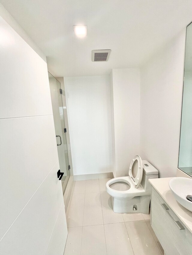 bathroom featuring toilet, tile patterned floors, vanity, and a shower with shower door