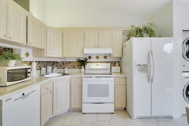 kitchen with stacked washer and clothes dryer, lofted ceiling, sink, light tile patterned floors, and white appliances