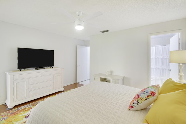 bedroom with ceiling fan, a textured ceiling, and light wood-type flooring