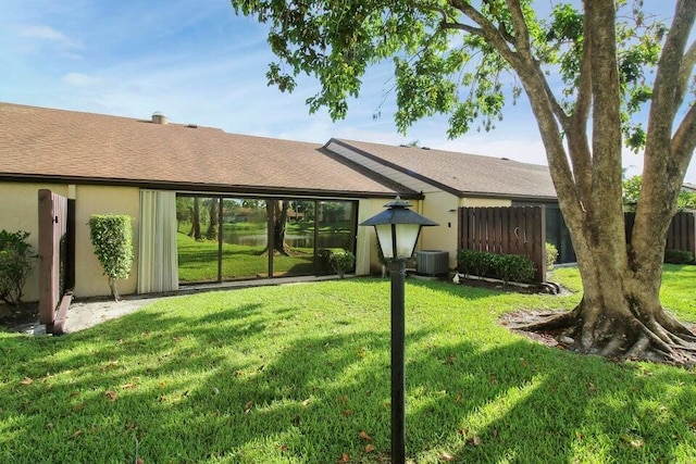 rear view of property featuring a yard and central air condition unit