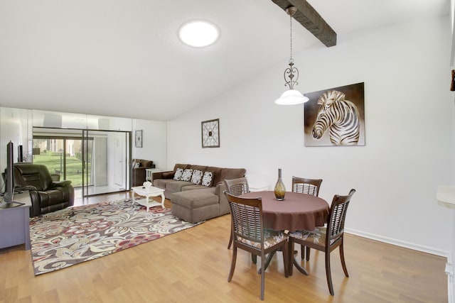 dining room featuring wood-type flooring and vaulted ceiling with beams