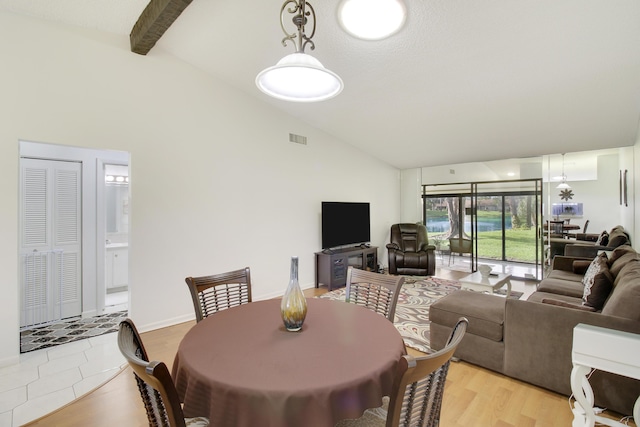 dining room featuring high vaulted ceiling, beamed ceiling, and light wood-type flooring