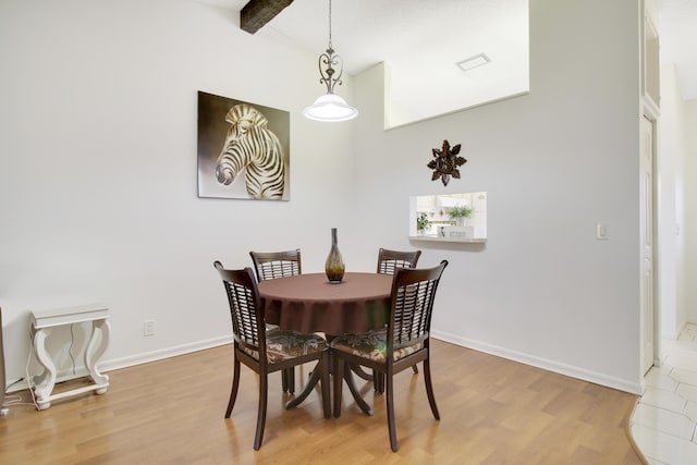 dining area featuring high vaulted ceiling, light wood-type flooring, and beam ceiling